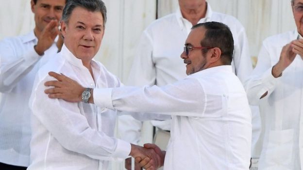 President Santos and Timochenko shaking hands after signing a peace deal