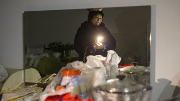 11月24日，60岁的王女士在北京周营一带等待帮忙搬家的人。