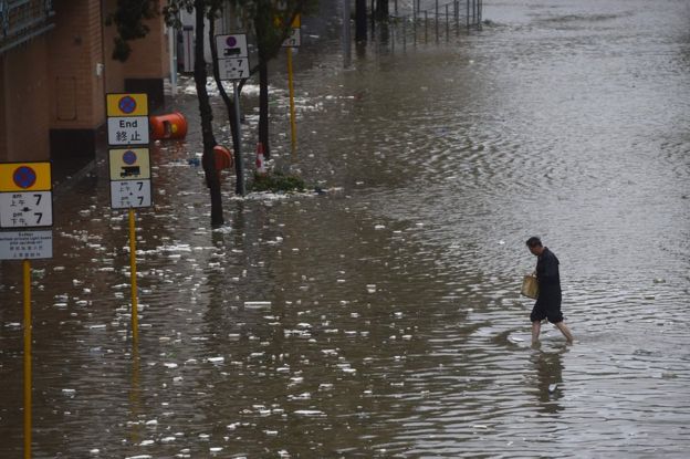 A man walks across a flooded street in the Heng Fa Chuen area as Typhoon Hato hits Hong Kong on 23 August 2017