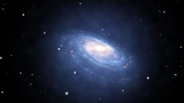 Artist's impression of a spiral galaxy with blue arms of dust and stars. A faint blue glow surrounds it.