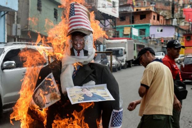 Un muñeco con fotos de Donald Trump y Mauricio Macri quemándose en el barrio 23 de enero de Caracas, Venezuela, el 16 de abril de 2017.