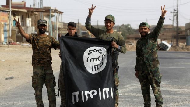 Iraqi members of the Hashed al-Shaabi (Popular Mobilisation units) carry an upsidedown Islamic State (IS) group flag in the city of al-Qaim, in Iraq