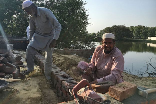 Raja Khan smiles as he works on the mosque