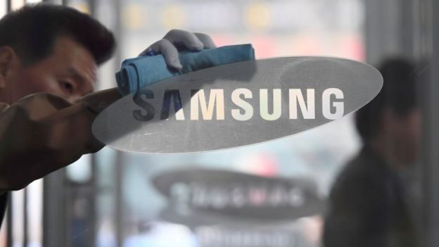un hombre limpia el logo de Samsung en el escaparate de una tienda.