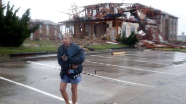 A woman walks away from a destroyed apartment building
