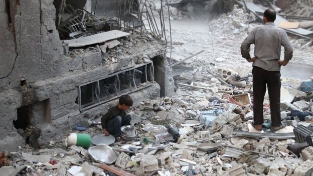 Un hombre y un niño de pie sobre las ruinas de una ciudad atacada