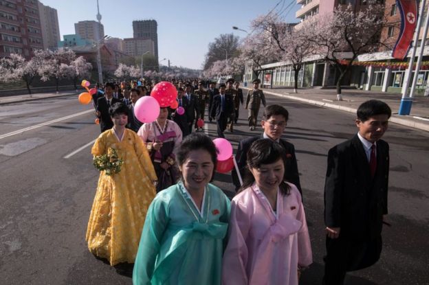 Os participantes que usam o vestido coreano tradicional fazem sua maneira à cerimónia de inauguração para o desenvolvimento da carcaça da rua de Ryomyong em Pyongyang em 13 abril 2017.