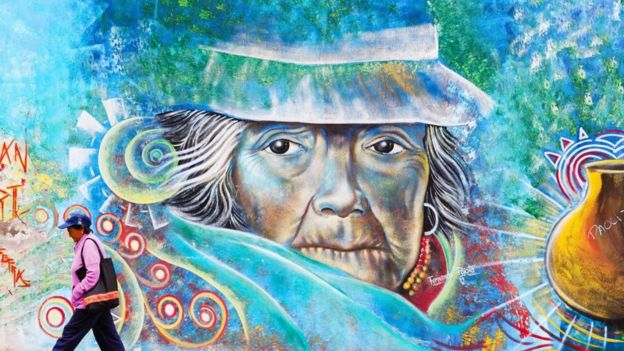 Una persona camina frente a un colorido grafiti en Ecuador
