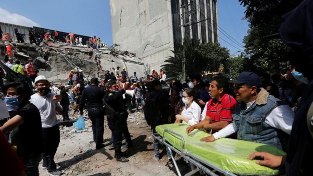 Equipos de rescate frente a un edificio derrumbado frente a un edificio que se mantuvo en pie en Ciudad de México.
