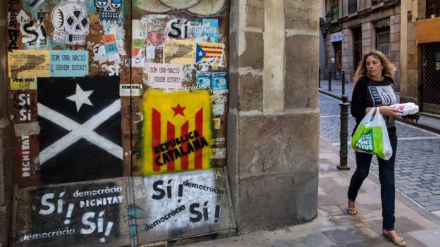 A woman walks past pieces of Catalan pro-independence graffiti on some doors in Barcelona