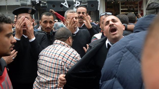 A group of Egyptian police personnel mourn outside the Saint Mark