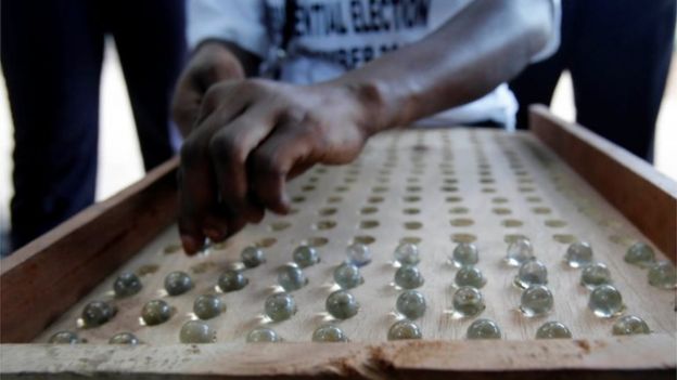 A poll worker counts votes cast by marbles after the close of voting during the presidential election in Banjul, Gambia, 1 December 2016.