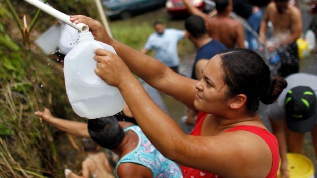 Una mujer en el oeste de San Juan rellena un envase desde una fuente natural ante la escasez de agua potable.