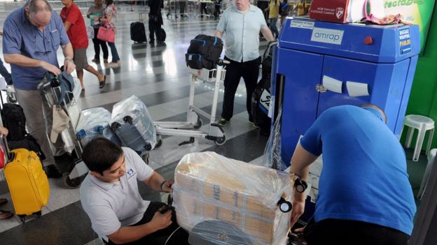 Passengers get their luggage wrapped in Manila airport on 4 November, 2015