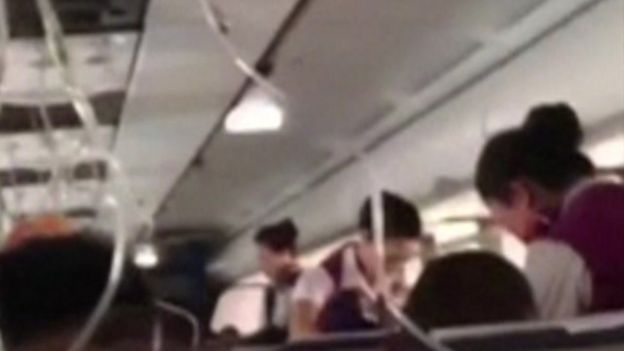 A still from mobile phone footage from the plane, showing oxygen masks in the plane