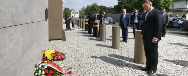 Polish President Andrzej Duda (R) bows after placing flowers in front of the British Embassy in Warsaw (23 May)