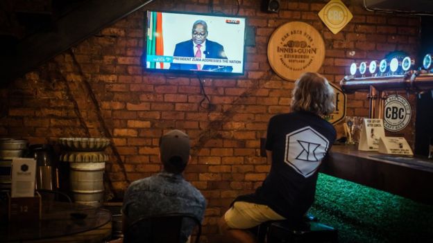 Dos hombres observan el mensaje televisado