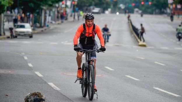 Un ciclista viaja por una carretera sin tráfico por la huelga en Caracas.