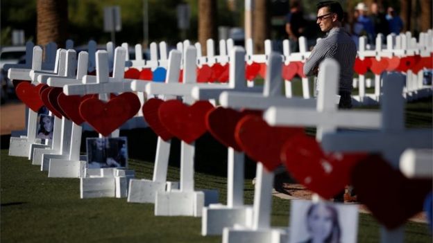 A man looks at the 58 white crosses displayed for the victims of the Route 91 music festival shooting in Las Vegas, Nevada.