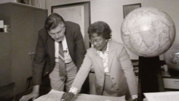 Gladys West in an office working with a male colleague