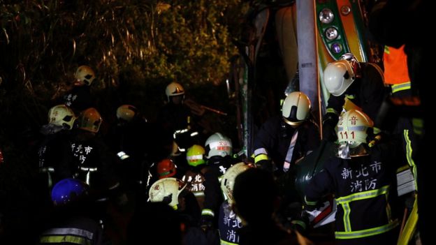 Rescuers look for survivors in a crashed bus after an accident on a highway in Taipei, Taiwan February 13, 2017
