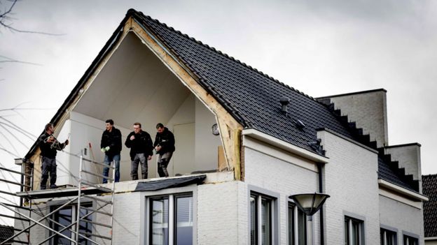 Builders on the first floor of a house after its wall was blown away by windstorms