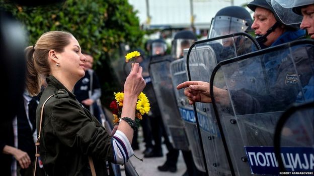 Una joven entrega una flor a un policía antimotines en protestas en Macedonia.
