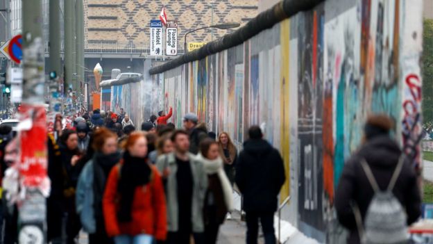 Turistas caminan frente a la galería del Lado Este, el remanente más grande del antiguo Muro de Berlín.