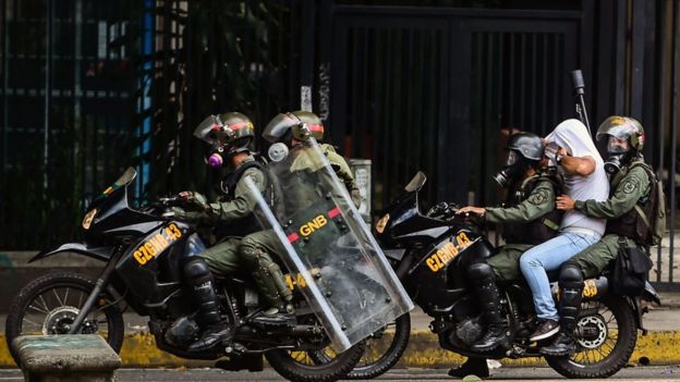 Funcionarios de la Guardia Nacional Bolivariana se llevan detenido a un manifestante.