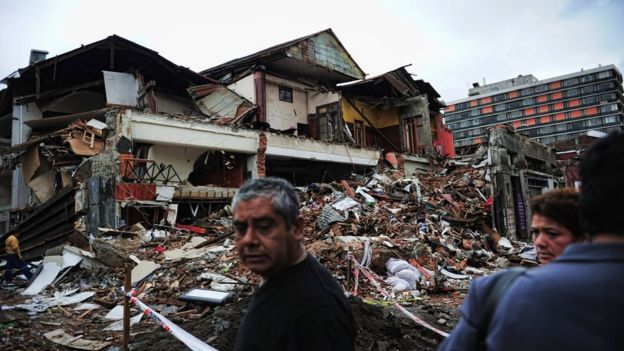 Personas observan edificios en escombros en Concepción, afectada por el terremoto de Chile de 2010.