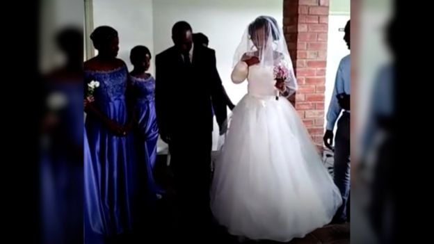 bride entering chapel at her dad's side, with right arm missing and stump bandaged