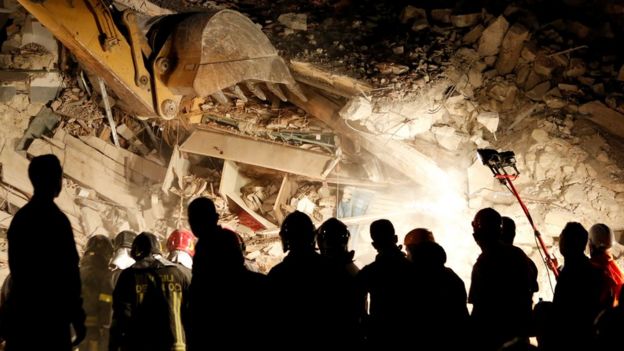 Rescuers work in the night at a collapsed house following an earthquake in Pescara del Tronto