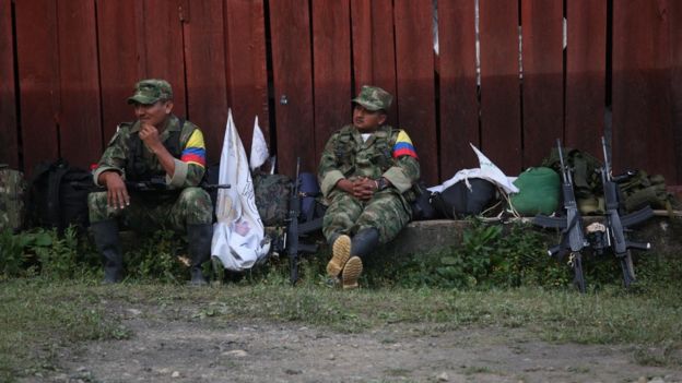 Guerrilleros sentados, cerca de unos fusiles.