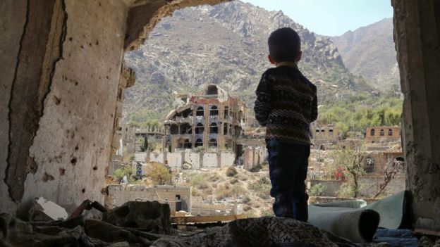 A Yemeni child looking out at buildings that were damaged in an air strike in the southern Yemeni city of Taez.
