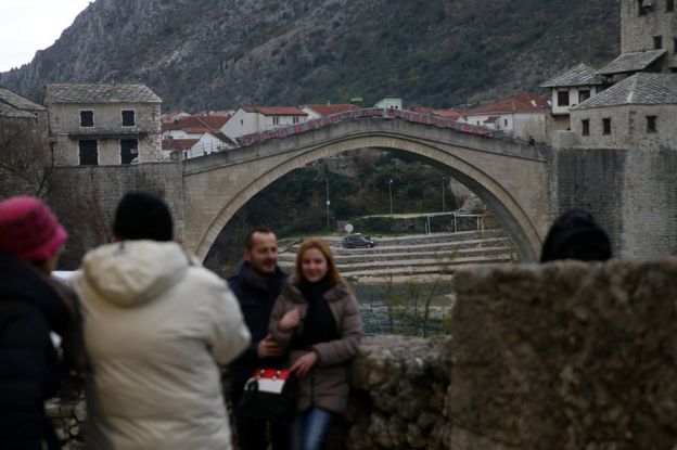 People take pictures in front of Mostar's Old Bridge