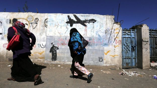 El 24 de diciembre de 2016 dos mujeres yemeníes pasan frente a un graffiti en Saná, pintado en protesta de los ataques con drone de Estados Unidos.