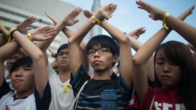 HONG KONG - OCTOBER 01: Student pro-democracy group Scholarism convenor Joshua Wong (C) makes a gesture at the Flag Raising Ceremony at Golden Bauhinia Square on October 1, 2014 in Hong Kong.