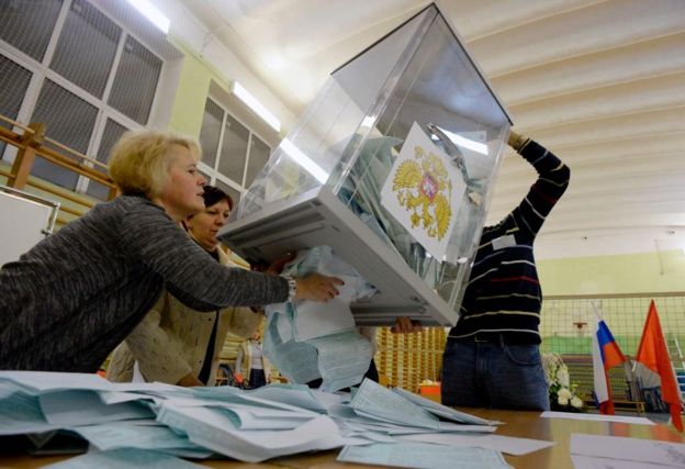 Personas con una urna llena de tarjetones.