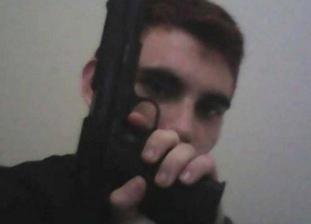 Nikolas Cruz, holding a gun in front of his face