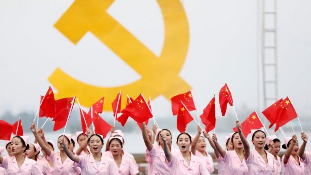 Mujeres chinas frente a un símbolo comunista