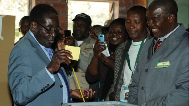 Zimbabwe President Robert Mugabe (L) casts his vote at a polling booth in a school in Harare on July 31, 2013.