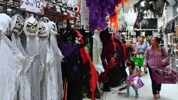 A family walks down an aisle of Halloween costumes