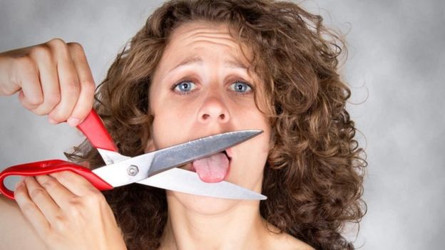 Una mujer que se va a cortar la lengua con una tijera