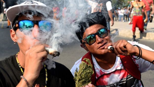 Dos jóvenes fumando marihuana en una marcha por la legalización