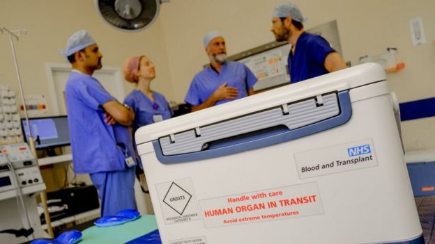 An organ in transit in a hospital room filled with doctors. Image copyright NHSBT