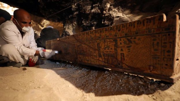 Egyptian antiquities worker brushes a coffin in a recently discovered tomb of Amenemhat, a goldsmith from the New Kingdom at the Draa Abu-el Naga