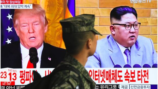 Un soldado surcoreano pasa junto a una pantalla con las imágenes de Trump y Kim Jong-un.