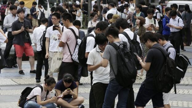 Gente en la calle con teléfonos celulares