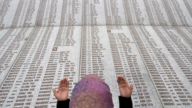 Una mujer llora frente a l memorial con los nombres de las víctimas de Srebrenica