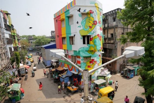 Indian commuters walk past a painted building at Sonagachi red light district in Kolkata,